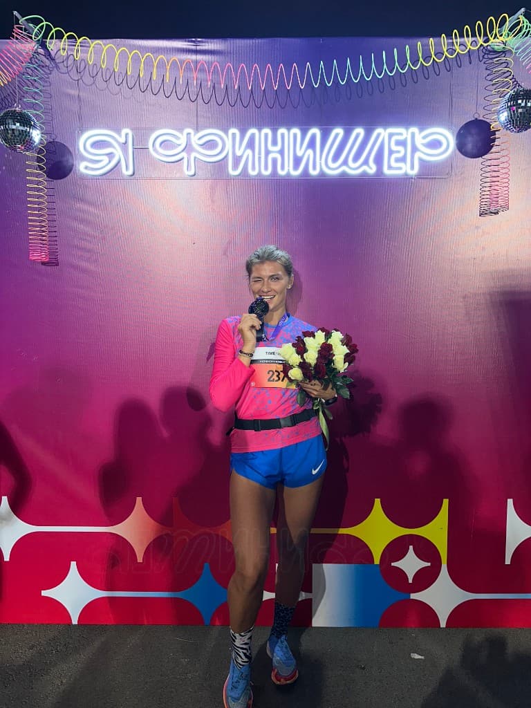 После финиша — основательница BY BOVT с медалью и букетом у неоновой надписи «Я ФИНИШЕР».